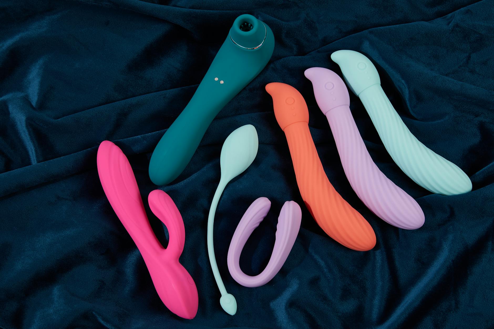 Colorful vibrators displayed on a bright yellow surface, showcasing different designs and shapes