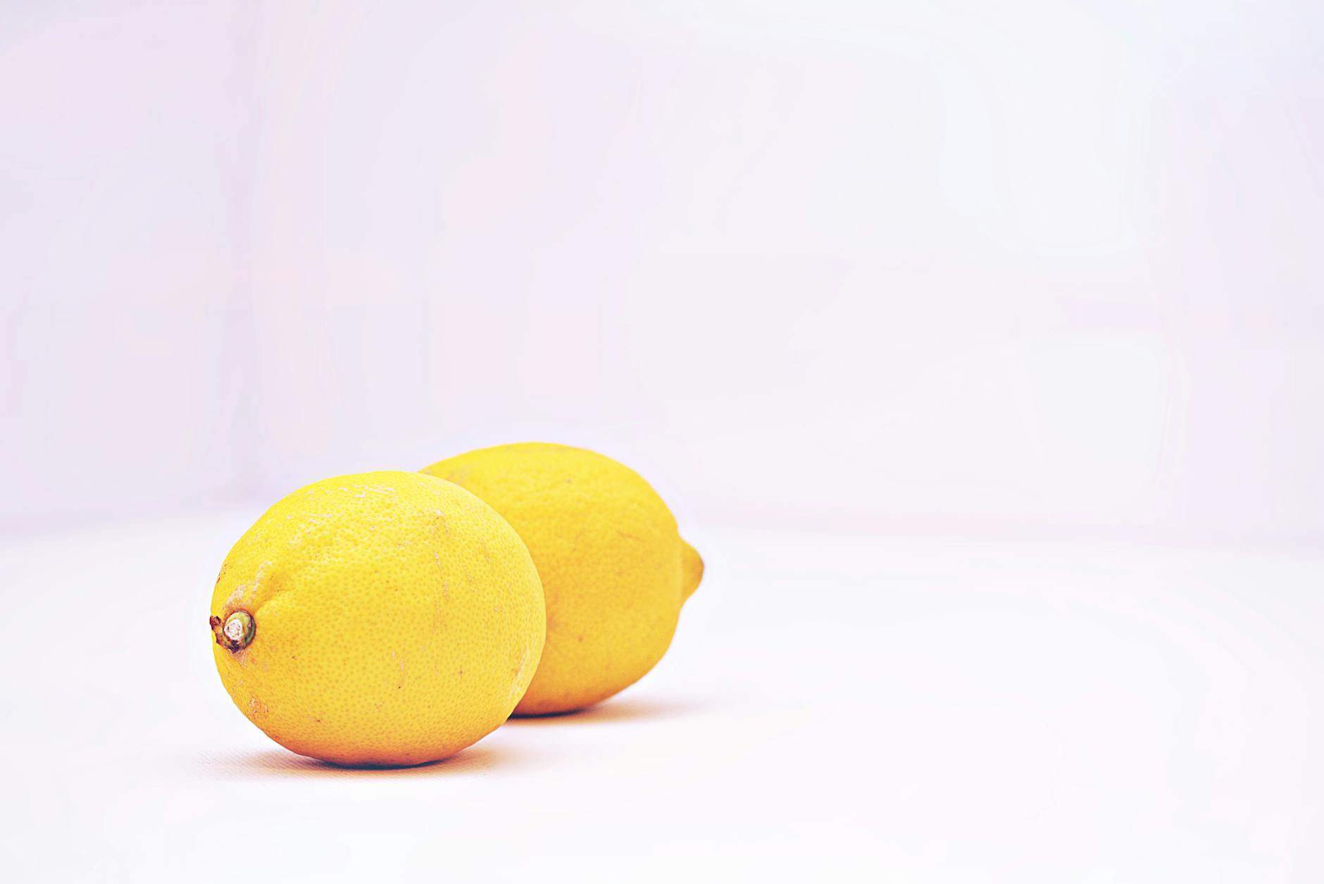 Hand holding a fresh lemon against a soft pink background, representing the slow, gradual nature of extended arousal