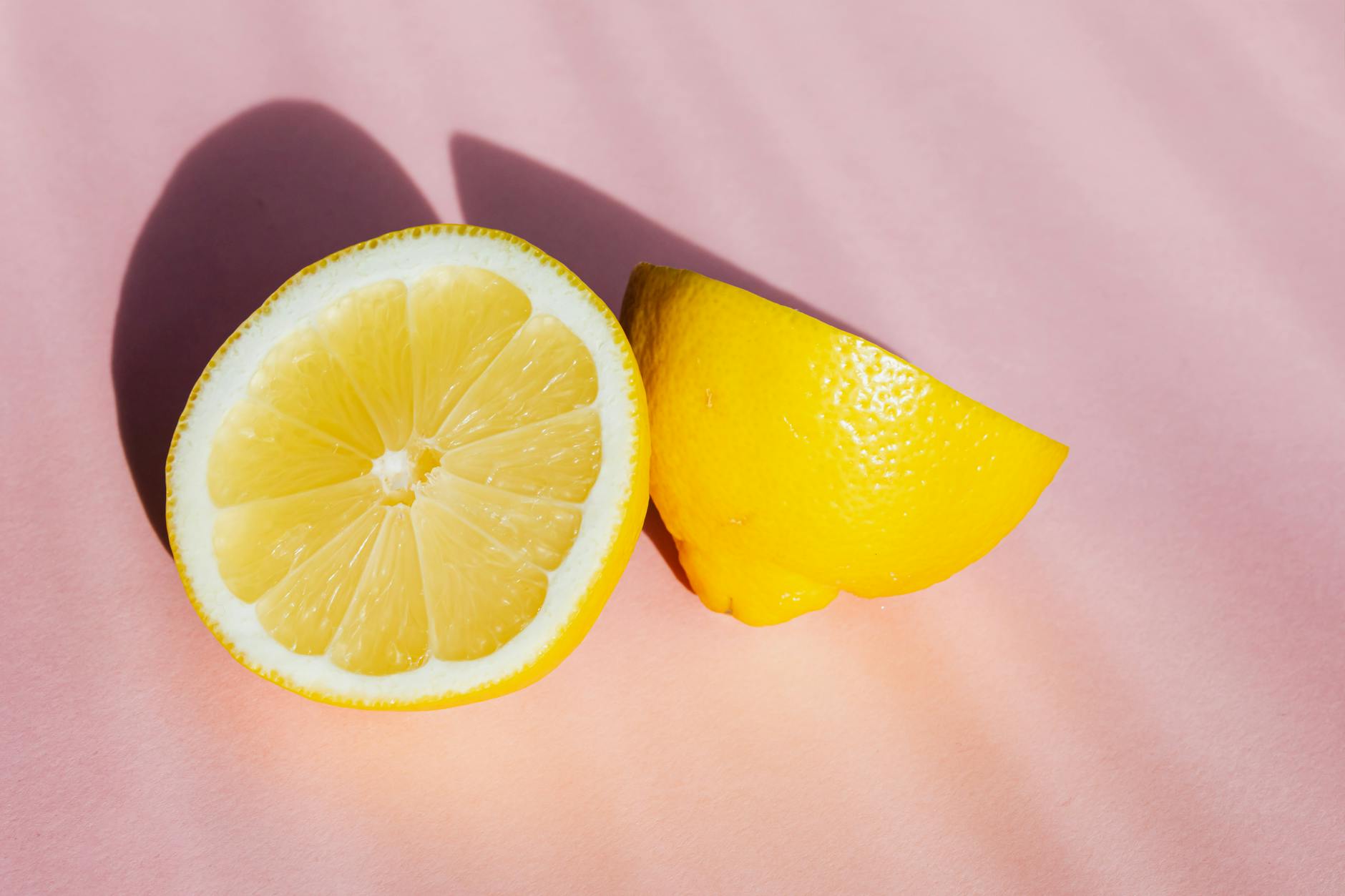 Fresh lemon halves on a pink background in sunlight, symbolizing quick hits of pleasure