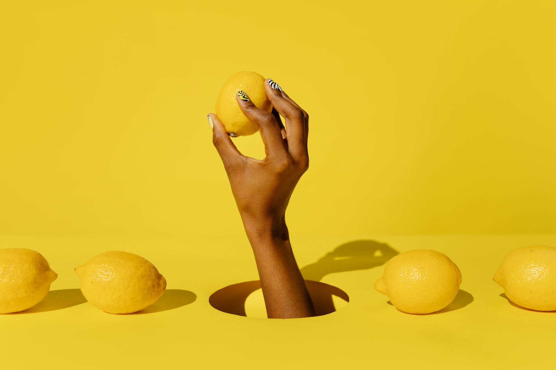 A hand holding a bright lemon against a vivid yellow background, symbolizing fresh communication and openness in intimate relationships.