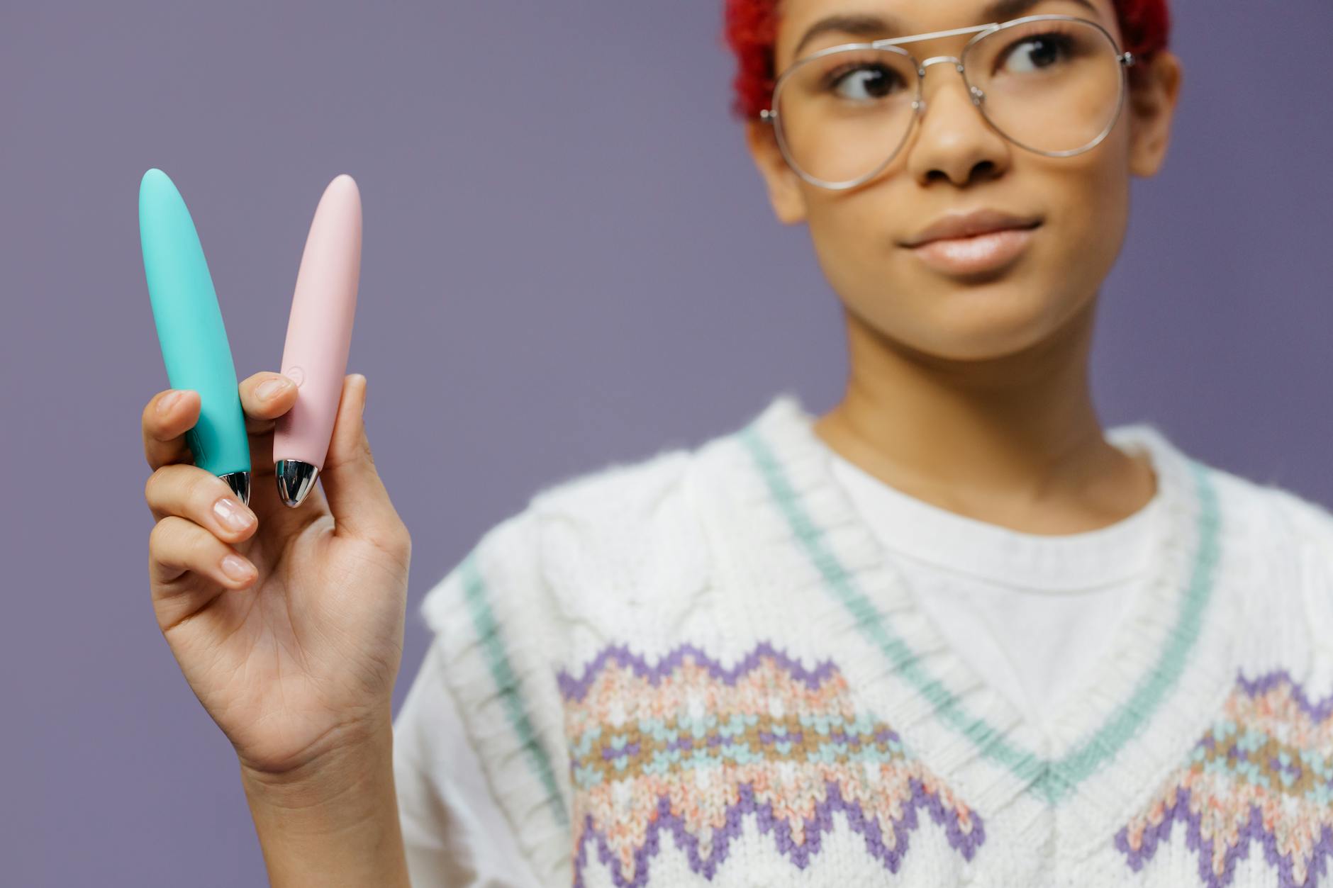Hand holding a blue silicone vibrator against a purple background, representing reclaiming pleasure during medication side effects