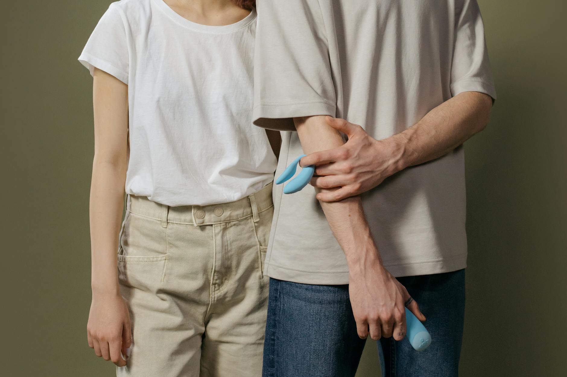 A couple standing together indoors, holding a blue vibrator, symbolizing modern intimacy and openness
