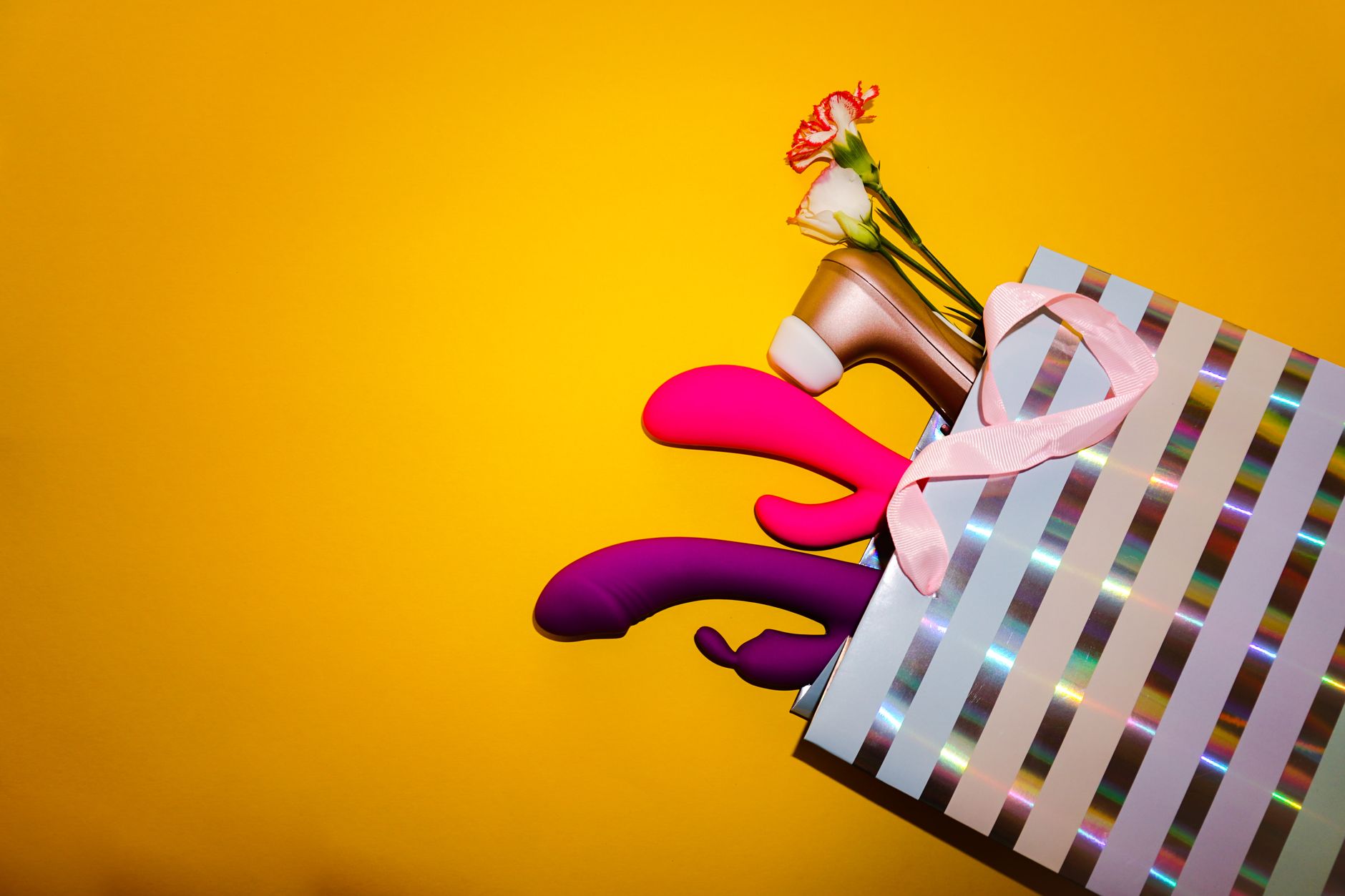 Colorful lemon vibrators arranged with fresh lemons and flowers against a bold yellow background