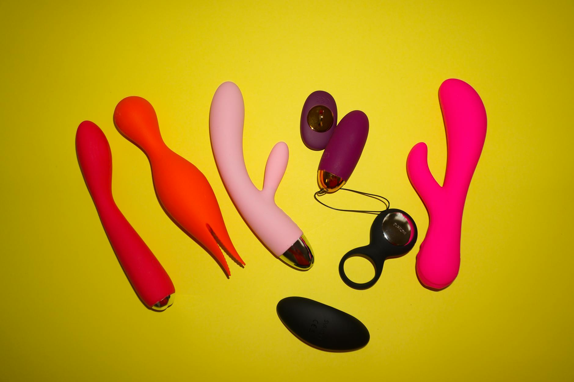 Colorful vibrators and intimate wellness tools arranged on a bright yellow background